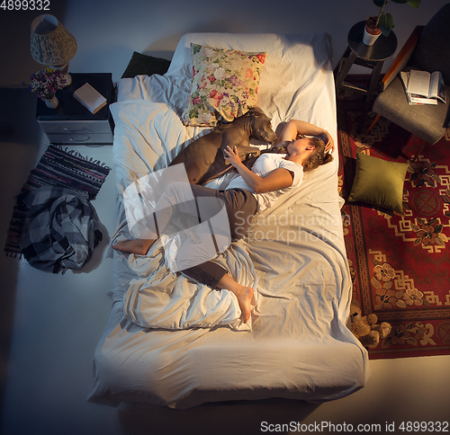 Image of Portrait of a woman, female breeder sleeping in the bed with her dog at home