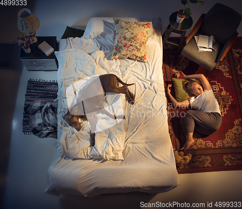 Image of Portrait of a woman, female breeder sleeping in the bed with her dog at home