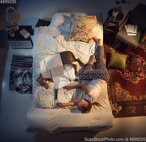 Image of Portrait of a woman, female breeder sleeping in the bed with her dog at home