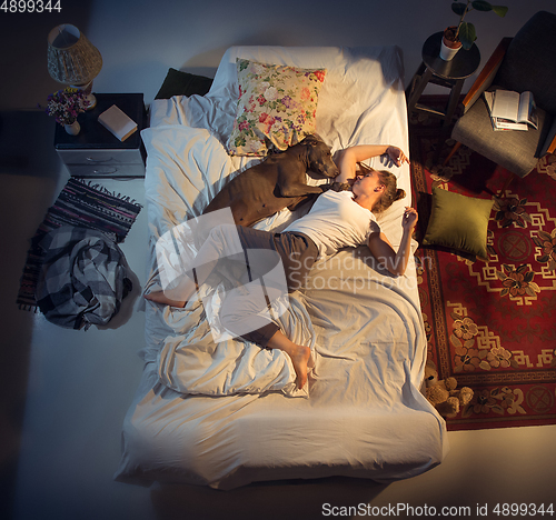 Image of Portrait of a woman, female breeder sleeping in the bed with her dog at home