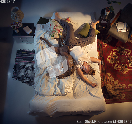 Image of Portrait of a woman, female breeder sleeping in the bed with her dog at home