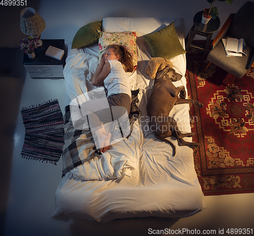 Image of Portrait of a woman, female breeder sleeping in the bed with her dog at home