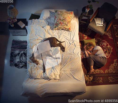 Image of Portrait of a woman, female breeder sleeping in the bed with her dog at home