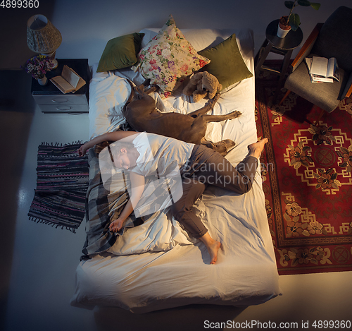 Image of Portrait of a woman, female breeder sleeping in the bed with her dog at home