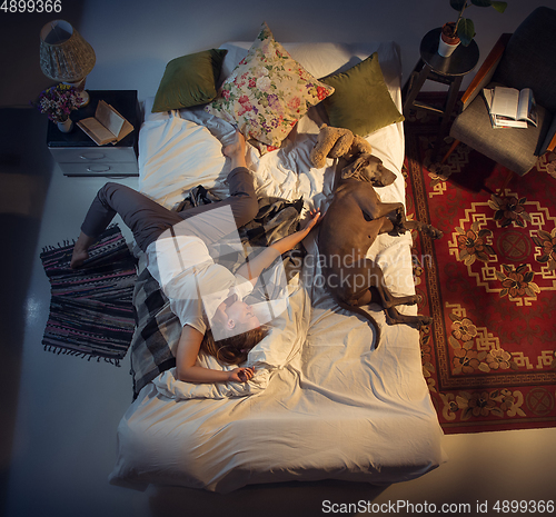 Image of Portrait of a woman, female breeder sleeping in the bed with her dog at home