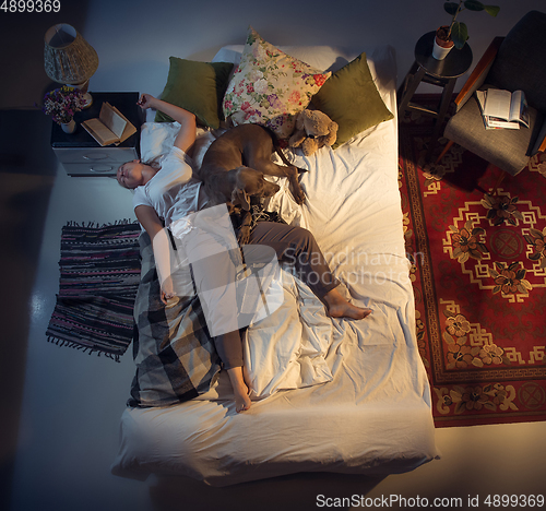 Image of Portrait of a woman, female breeder sleeping in the bed with her dog at home