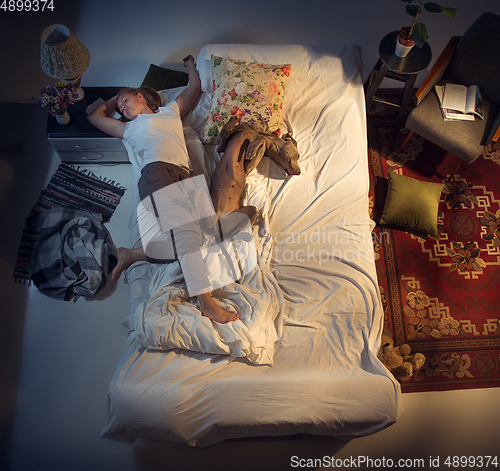 Image of Portrait of a woman, female breeder sleeping in the bed with her dog at home