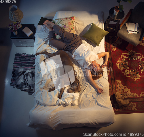 Image of Portrait of a woman, female breeder sleeping in the bed with her dog at home