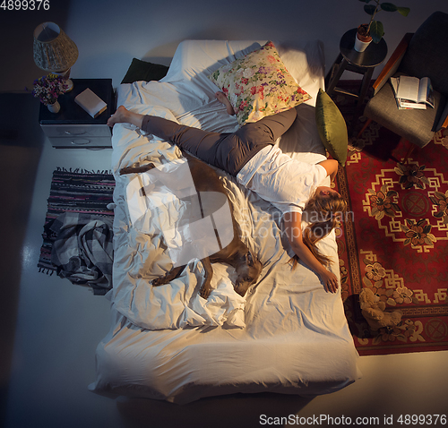 Image of Portrait of a woman, female breeder sleeping in the bed with her dog at home