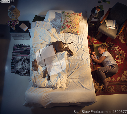 Image of Portrait of a woman, female breeder sleeping in the bed with her dog at home