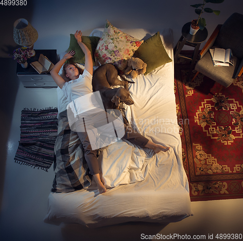 Image of Portrait of a woman, female breeder sleeping in the bed with her dog at home