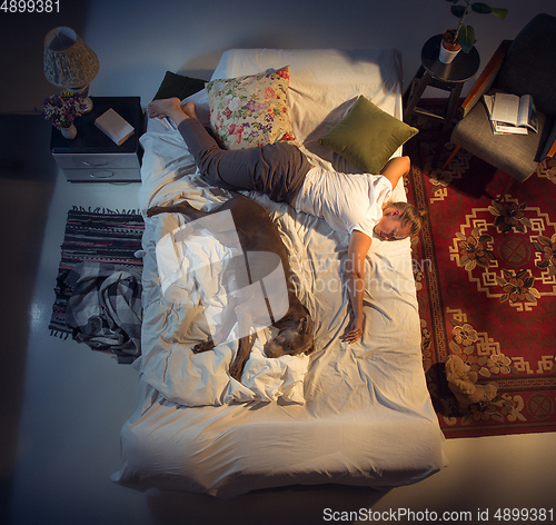 Image of Portrait of a woman, female breeder sleeping in the bed with her dog at home