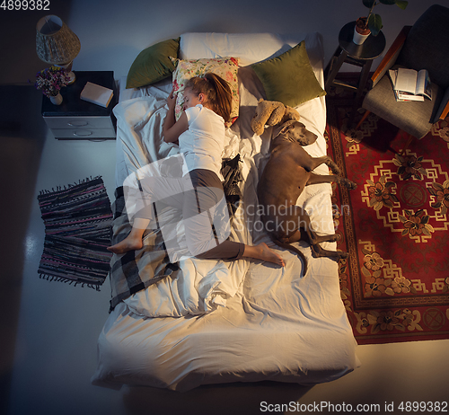 Image of Portrait of a woman, female breeder sleeping in the bed with her dog at home