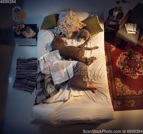 Image of Portrait of a woman, female breeder sleeping in the bed with her dog at home