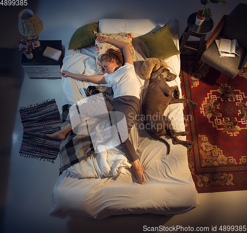 Image of Portrait of a woman, female breeder sleeping in the bed with her dog at home