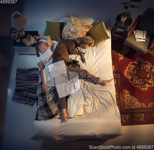 Image of Portrait of a woman, female breeder sleeping in the bed with her dog at home