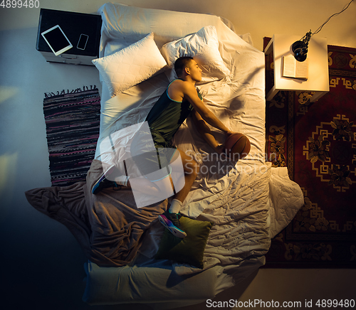 Image of Top view of young professional basketball player sleeping at his bedroom in sportwear with ball