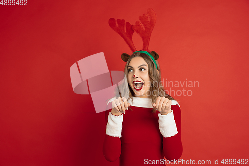 Image of Beautiful woman like Christmas deer isolated on red background. Concept of 2021 New Year\'s, winter mood, holidays.