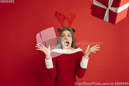 Image of Beautiful woman like Christmas deer isolated on red background. Concept of 2021 New Year\'s, winter mood, holidays.