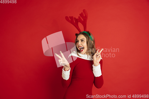 Image of Beautiful woman like Christmas deer isolated on red background. Concept of 2021 New Year\'s, winter mood, holidays.