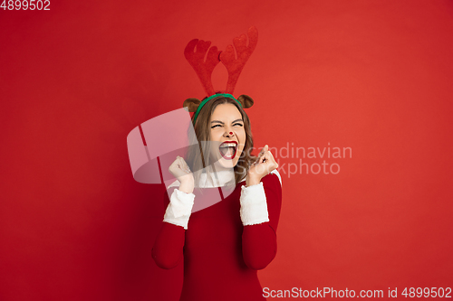 Image of Beautiful woman like Christmas deer isolated on red background. Concept of 2021 New Year\'s, winter mood, holidays.