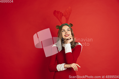 Image of Beautiful woman like Christmas deer isolated on red background. Concept of 2021 New Year\'s, winter mood, holidays.