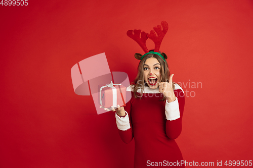 Image of Beautiful woman like Christmas deer isolated on red background. Concept of 2021 New Year\'s, winter mood, holidays.