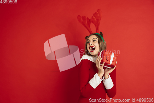 Image of Beautiful woman like Christmas deer isolated on red background. Concept of 2021 New Year\'s, winter mood, holidays.