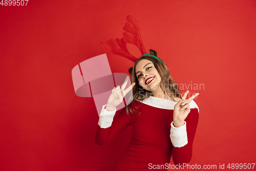 Image of Beautiful woman like Christmas deer isolated on red background. Concept of 2021 New Year\'s, winter mood, holidays.