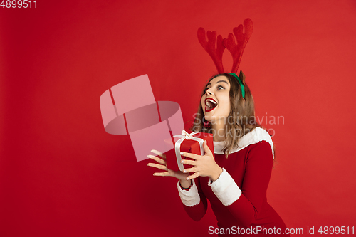 Image of Beautiful woman like Christmas deer isolated on red background. Concept of 2021 New Year\'s, winter mood, holidays.