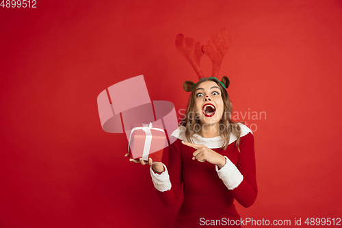 Image of Beautiful woman like Christmas deer isolated on red background. Concept of 2021 New Year\'s, winter mood, holidays.