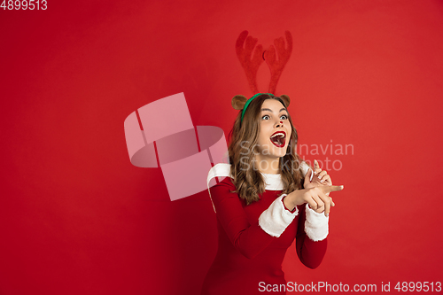 Image of Beautiful woman like Christmas deer isolated on red background. Concept of 2021 New Year\'s, winter mood, holidays.