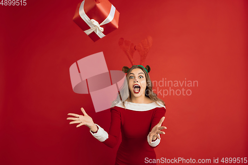 Image of Beautiful woman like Christmas deer isolated on red background. Concept of 2021 New Year\'s, winter mood, holidays.