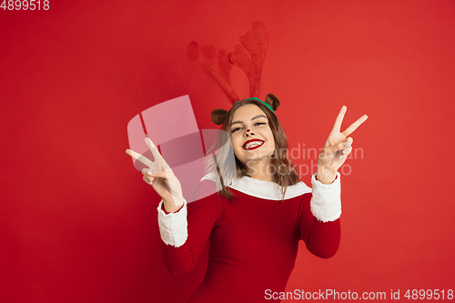 Image of Beautiful woman like Christmas deer isolated on red background. Concept of 2021 New Year\'s, winter mood, holidays.