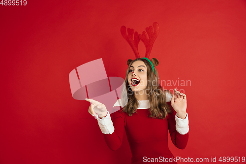 Image of Beautiful woman like Christmas deer isolated on red background. Concept of 2021 New Year\'s, winter mood, holidays.