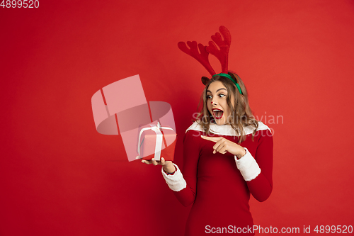 Image of Beautiful woman like Christmas deer isolated on red background. Concept of 2021 New Year\'s, winter mood, holidays.