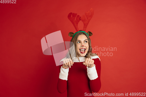 Image of Beautiful woman like Christmas deer isolated on red background. Concept of 2021 New Year\'s, winter mood, holidays.