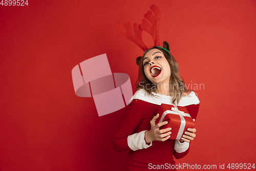 Image of Beautiful woman like Christmas deer isolated on red background. Concept of 2021 New Year\'s, winter mood, holidays.