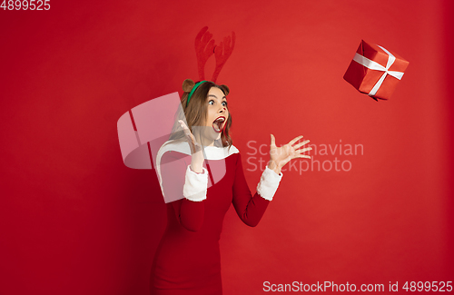 Image of Beautiful woman like Christmas deer isolated on red background. Concept of 2021 New Year\'s, winter mood, holidays.