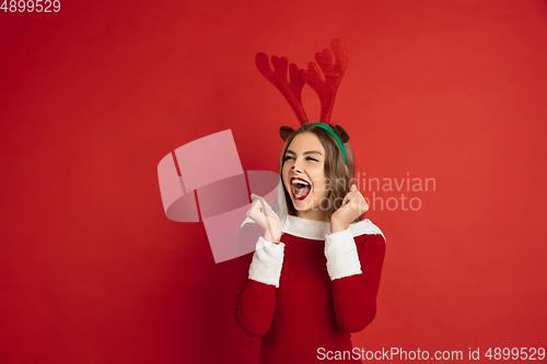 Image of Beautiful woman like Christmas deer isolated on red background. Concept of 2021 New Year\'s, winter mood, holidays.