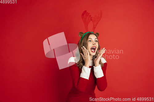 Image of Beautiful woman like Christmas deer isolated on red background. Concept of 2021 New Year\'s, winter mood, holidays.