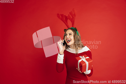 Image of Beautiful woman like Christmas deer isolated on red background. Concept of 2021 New Year\'s, winter mood, holidays.