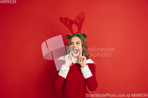 Image of Beautiful woman like Christmas deer isolated on red background. Concept of 2021 New Year\'s, winter mood, holidays.