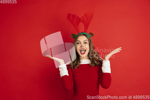 Image of Beautiful woman like Christmas deer isolated on red background. Concept of 2021 New Year\'s, winter mood, holidays.