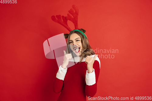 Image of Beautiful woman like Christmas deer isolated on red background. Concept of 2021 New Year\'s, winter mood, holidays.