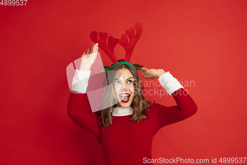 Image of Beautiful woman like Christmas deer isolated on red background. Concept of 2021 New Year\'s, winter mood, holidays.