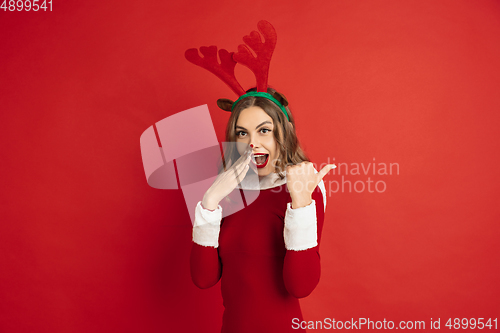 Image of Beautiful woman like Christmas deer isolated on red background. Concept of 2021 New Year\'s, winter mood, holidays.