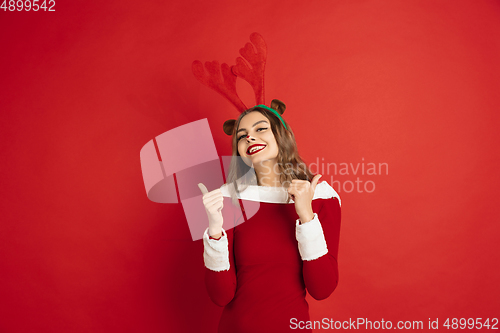 Image of Beautiful woman like Christmas deer isolated on red background. Concept of 2021 New Year\'s, winter mood, holidays.