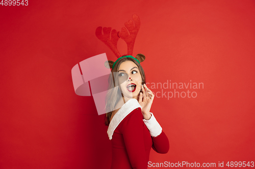 Image of Beautiful woman like Christmas deer isolated on red background. Concept of 2021 New Year\'s, winter mood, holidays.