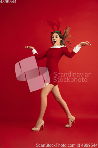 Image of Beautiful woman like Christmas deer isolated on red background. Concept of 2021 New Year\'s, winter mood, holidays.